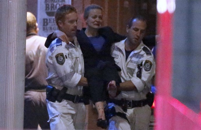 Police rescue personnel carry an injured woman from the Lindt cafe, where hostag