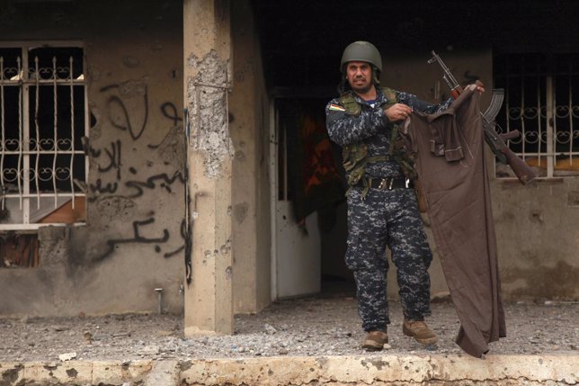 Un peshmerga kurdo sujeta la prenda de un combatiente de EI