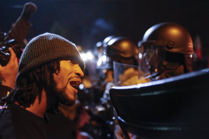 Un manifestante le grita a un policía en Ferguson.