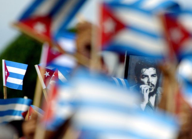 CUBANS WAVING FLAGS AROUND A PICTURE OF CHE GUEVARA DURING RALLY.