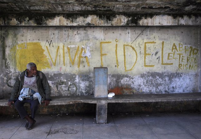 A man sits near graffiti reading 