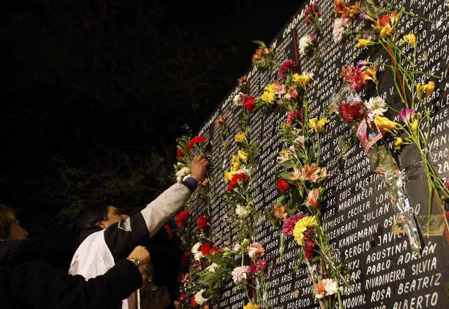 A relative of a victim of a nightclub fire places flowers on a board with the vi