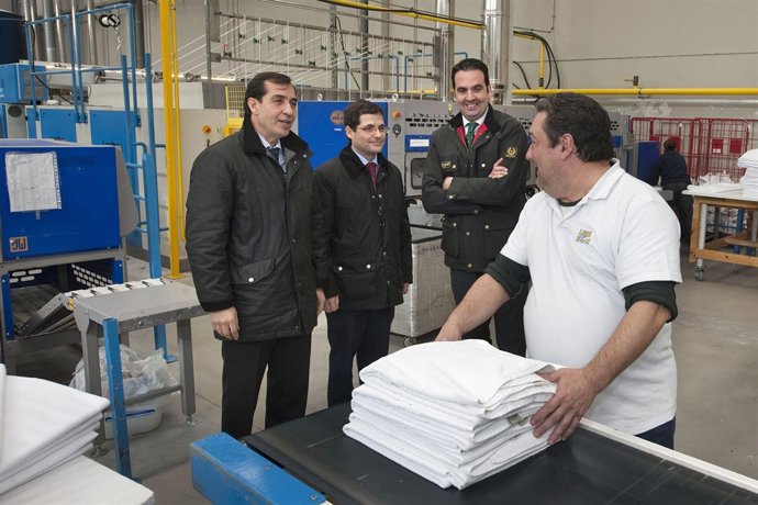 El consejero Alli y directivos de la empresa charlan con un empleado.
