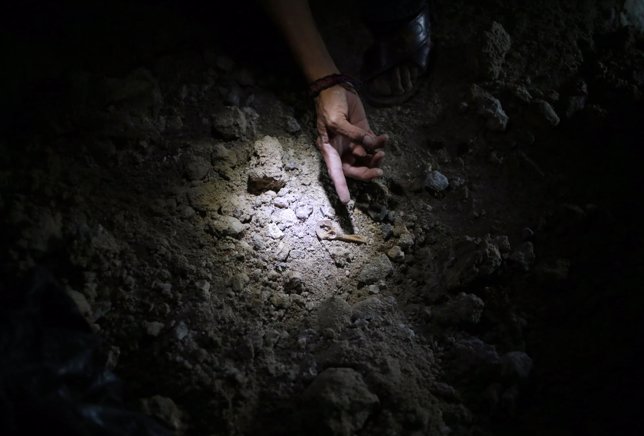 A man with missing relatives points at bone found in the cave called 