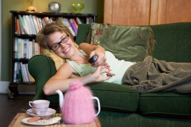 Mujer en sofá con tetera y viendo la tele