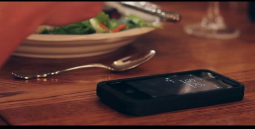Una mujer come con su iPhone sobre la mesa.