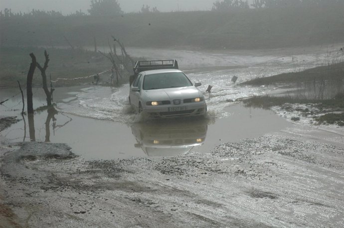 Vehículo atravesando el vado inundado por lluvias del pantano de Los Palacios