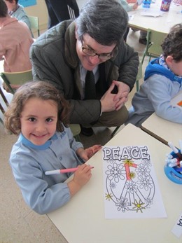 El consejero observa el cartel que prepara una alumna del colegio.