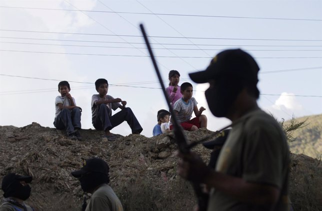 Un grupo de niños observa a varios hombres armados