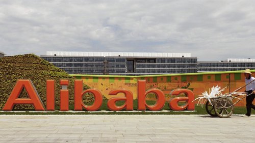 Un trabajador pasa junto al logo del grupo de internet Alibaba