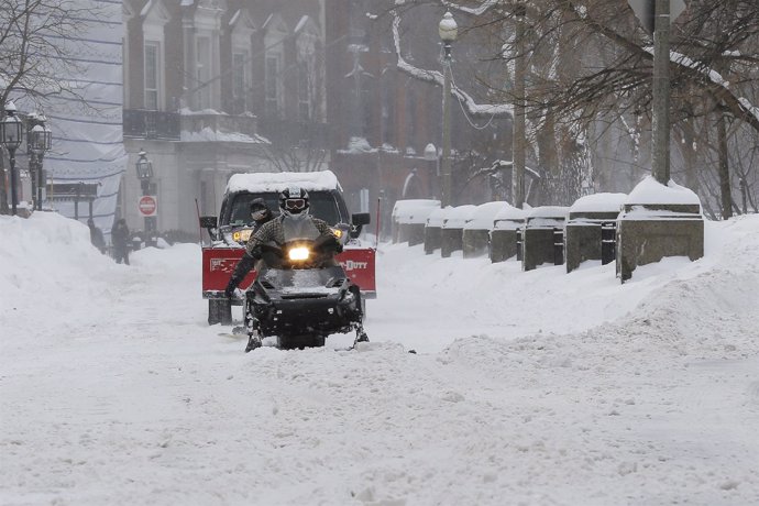 Snow-mobiler pulls a man on snow board on Commonwealth Avenue in Boston