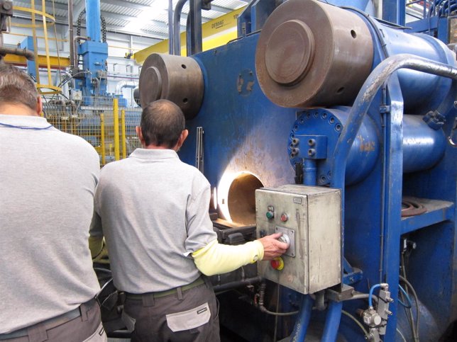Dos operarios manipulando una máquina en una fábrica.