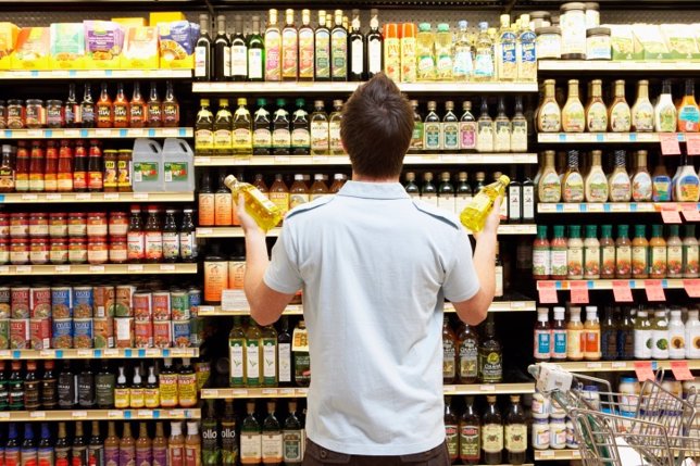 Un hombre comprando en un supermercado mirando los aditivos