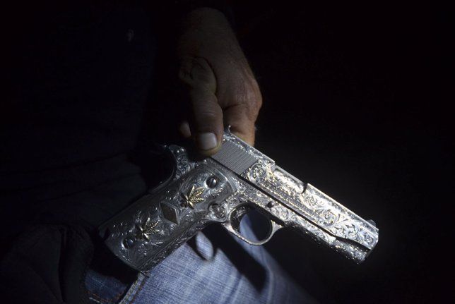 Un ex miembro del cártel de drogas, convertido en vigilante, muestra su arma
