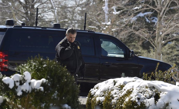 A Secret Service officer radios as a motorcade vehicle prepares to take U.S. Pre