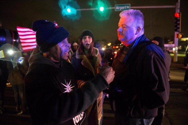Protesters confront police at an intersection after a man was fatally shot by a 