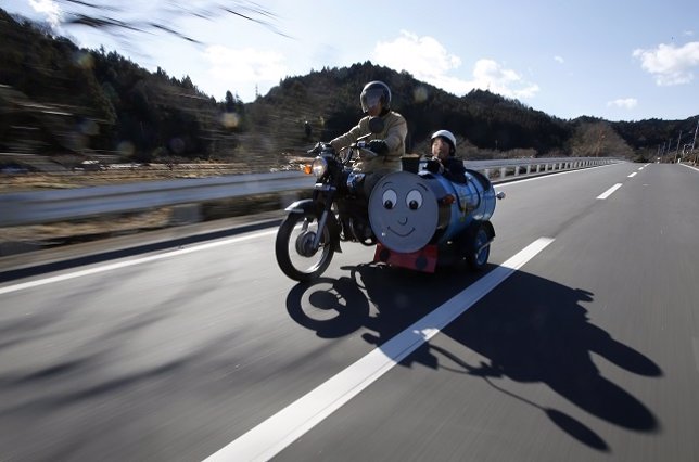 Sadao Kimbara rides on a Honda motorcycle with a sidecar he made out of an oil b