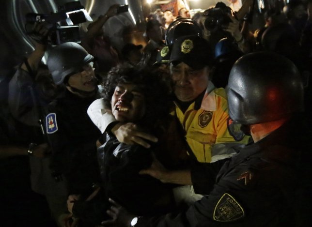 A protester is detained by riot police after a protest march to demand justice f