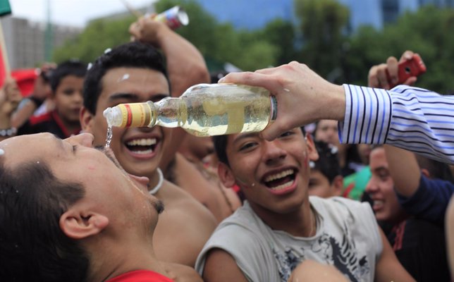 A Mexican fan drinks tequila as he celebrates his team's victory against France 