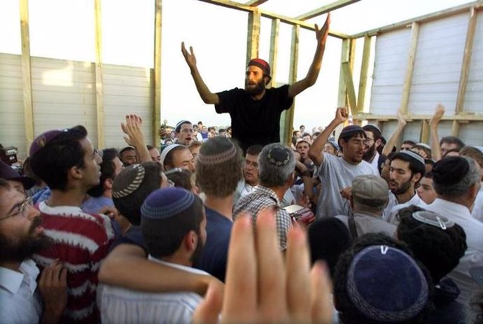Colonos judíos celebran y oran tras instalar una pieza de una nueva sinagoga