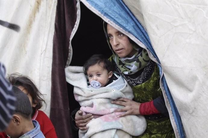 Mujer y su bebé se refugian del frío en este campo de refugiados en Turquía.
