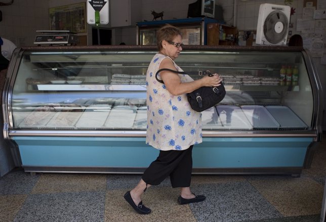 A customer walks past a butcher's empty display counter in Caracas