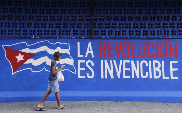 Un niño pasa junto a un graffiti " La revolución es invencible " en La Habana 