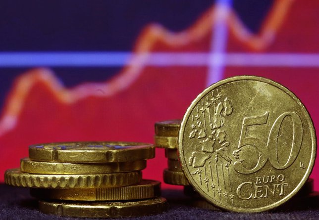 Euro coins are seen in front of a displayed stock graph in this picture illustra