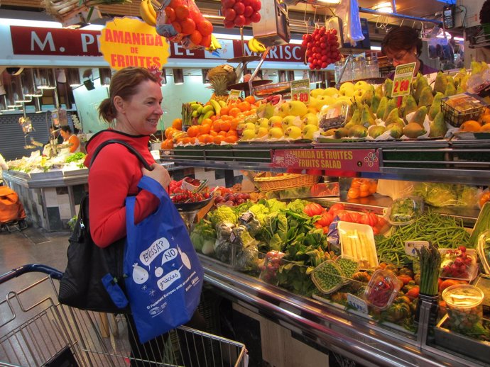 Una mujer va a comprar en el Mercado de la Concepció con una bolsa reciclable
