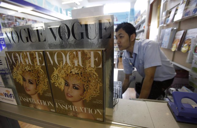 A bookseller works near copies of the Thai edition of Vogue magazine as he waits