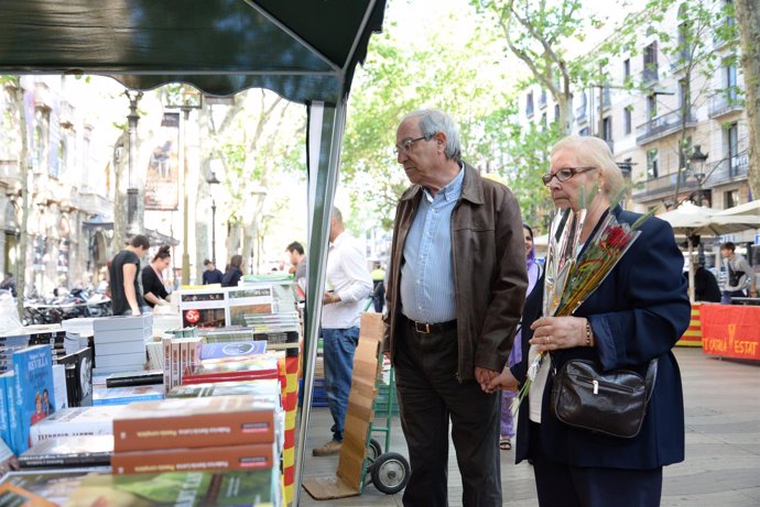 Pareja con una rosa en un 'stand' de libros por Sant Jordi