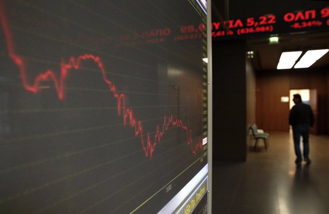 A man walks inside Athens stock exchange as a monitor shows the general index