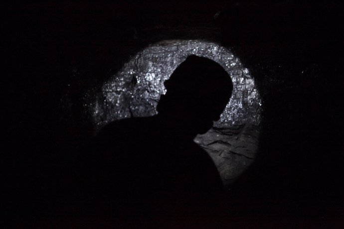 A miner points his headlight on a wall inside an unregulated coal mine in Sabina