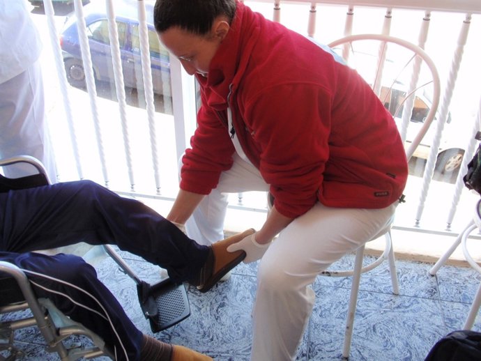 Una trabajadora sanitaria atiende a una pesona dependiente  