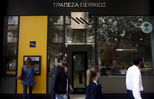 A customer uses an ATM outside a branch of Piraeus Bank in Athens