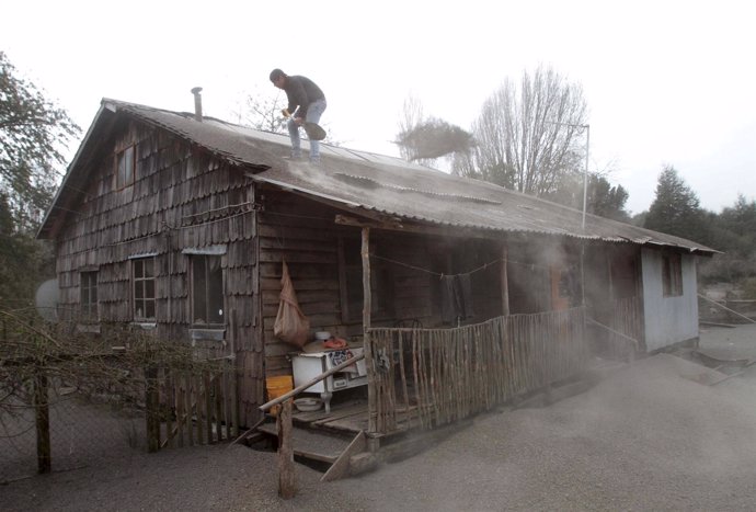 Un hombre retira la ceniza del volcán Calbuco del tejado de su casa. 