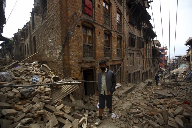 Un hombre delante de casas derruidas por terremoto en Nepal