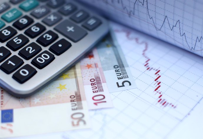 Euro banknotes coins and a calculator are placed on a currency graph and ticker 