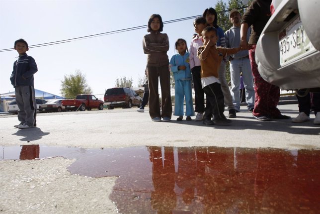 Children look at a puddle of blood at a crime scene in Ciudad Juarez