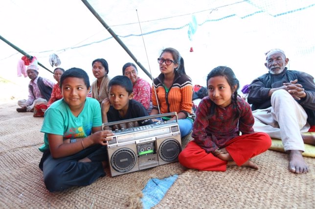Niños y adultos escuchan la radio tras el terremoto de Nepal