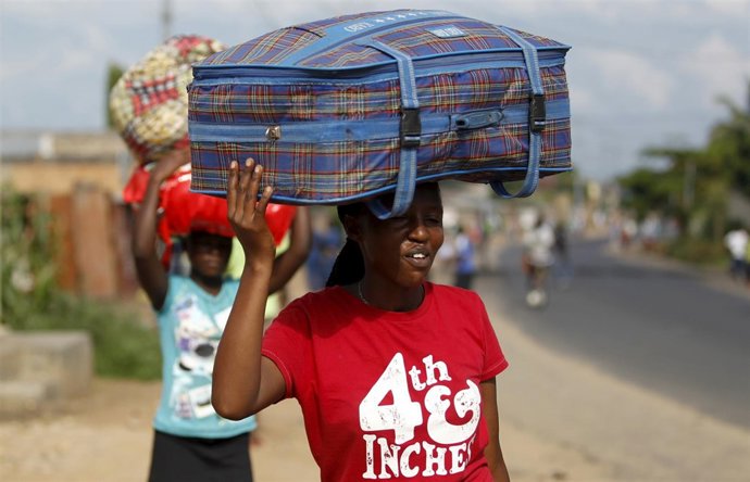 Women carry their belongings as they flee in fear of recent clashes between riot