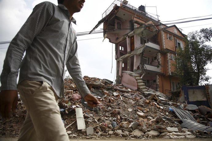Un hombre delante de un edificio derrumbado por terremoto de Nepal