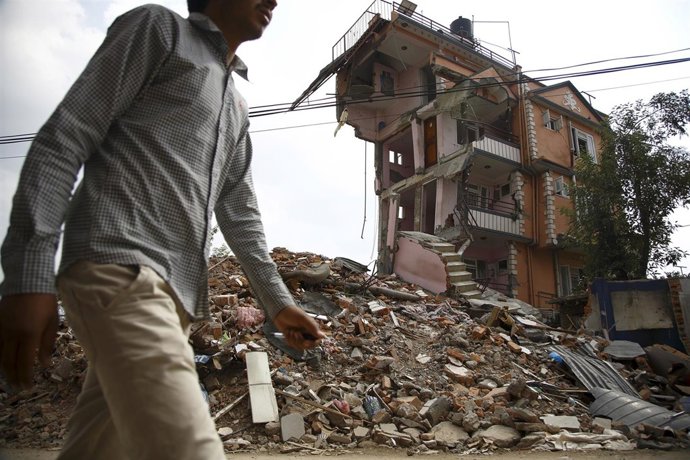 Un hombre delante de un edificio derrumbado por terremoto de Nepal