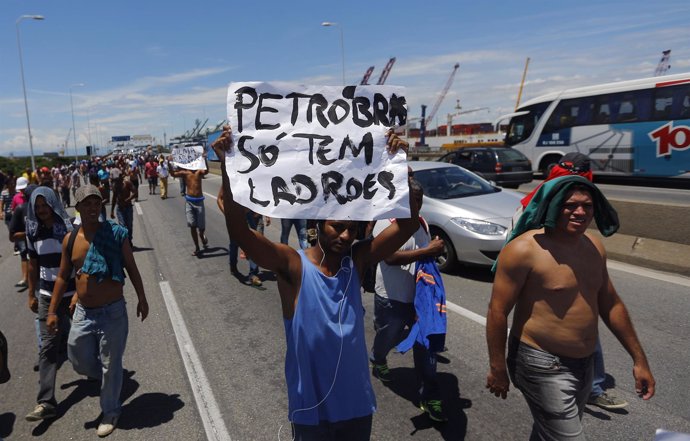 An outsourced worker who was contracted to work for Petrobras holds a placard as