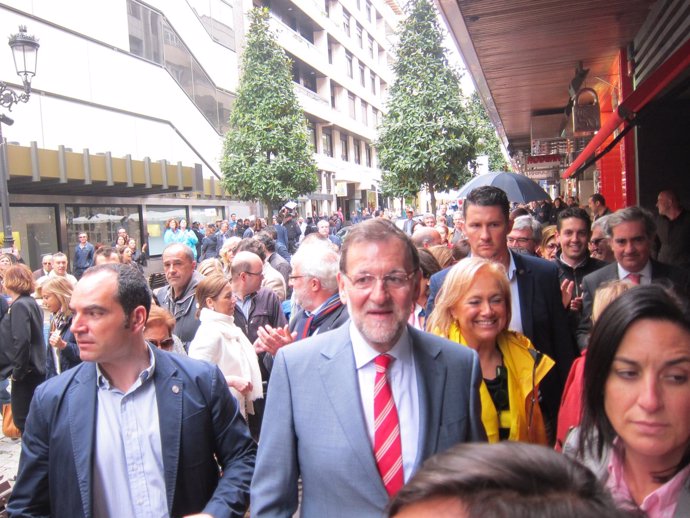 Rajoy, durante su paseo por Oviedo. Al fondo, las protestas. 