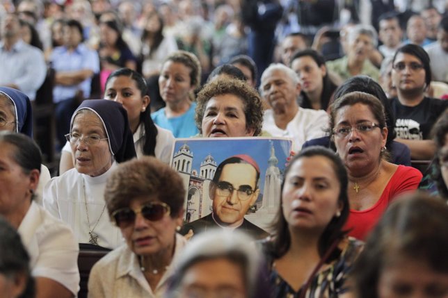 Woman holds picture of late Archbishop Romero during a mass to commemorate the 3