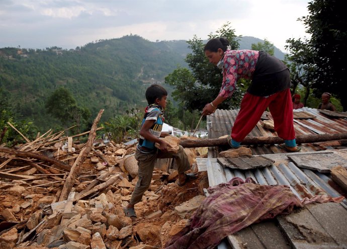 Un niño ayuda a su madre a reconstruir su casa en Sindhupalchowk, Nepal