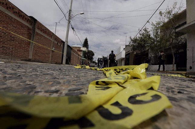Yellow police tape lies on the road as federal agents work at a crime scene in t