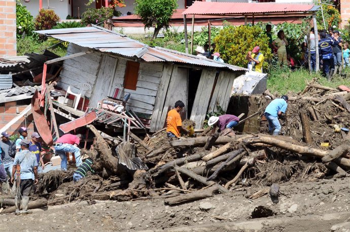 Residents remove mud and debris as they search for bodies after a landslide in t