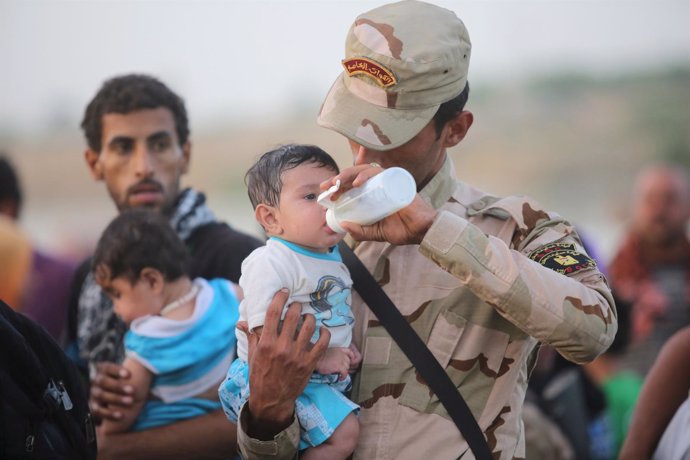 Un soldado iraquí alimenta a un bebé desplazado por el Estado Islámico